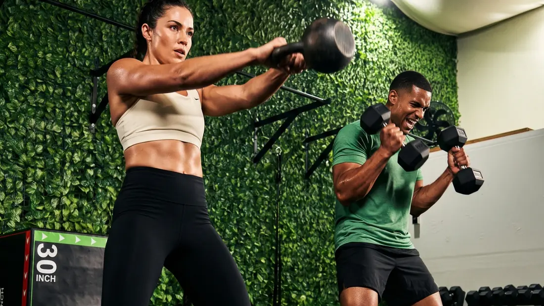 Entrenamiento funcional en SYBA: swing con pesa rusa y curl con mancuernas frente al muro verde